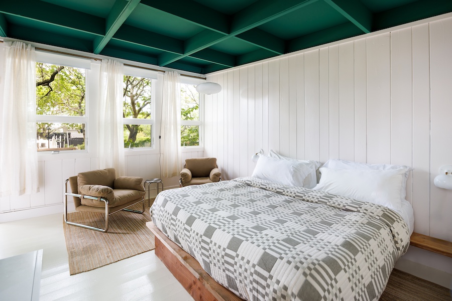 Ruschmeyer’s montauk long island new york summer camp lodging coastal white board and batten wainscoting green coffered ceiling bed brown armchairs