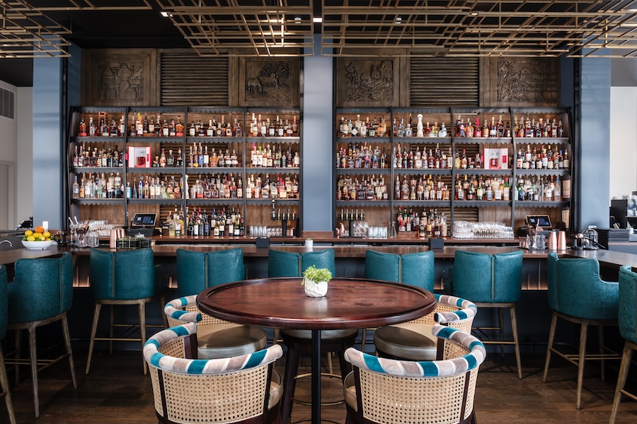 Hotel Bourré Bonne Curio Collection by Hilton kentucky french bourbon design restaurant teal blue bar stools liquor shelf rattan dining chairs