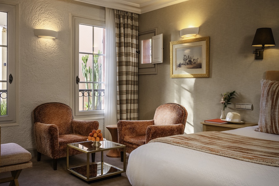 Hotel Byblos Saint-Tropez stone plaster orange armchairs guestroom bed picture frame wall sconce