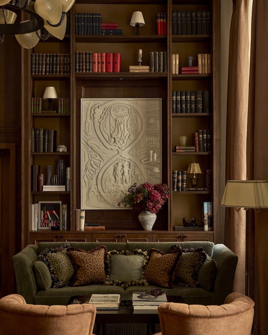 Sir Prague library built in bookshelf niches wall art green sofa pillows