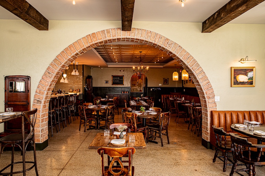 Cane Pazzo charleston south carolina italian osteria main dining room coffered ceiling chandelier brick arch doorway exposed wood beam ceiling