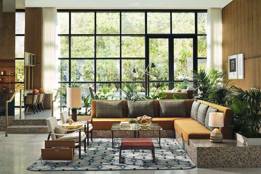 the hollywood grande los angeles former thompson hotel midcentury design lobby bar fluted glass chandeliers built in shelving banquette seating glass coffee table floor to ceiling windows