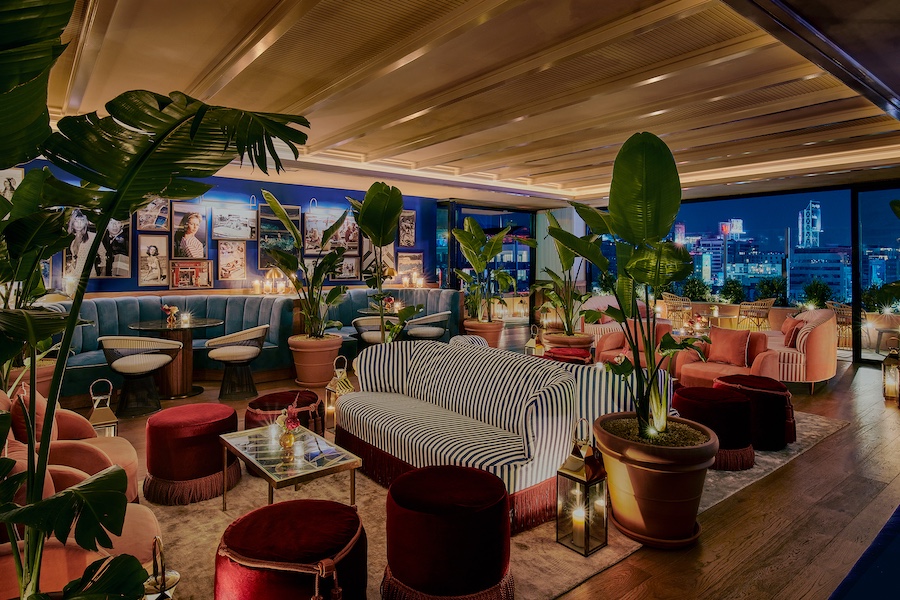 the hollywood grande los angeles former thompson hotel midcentury design bar lis indoor plants striped sofa red velvet ottomans city views