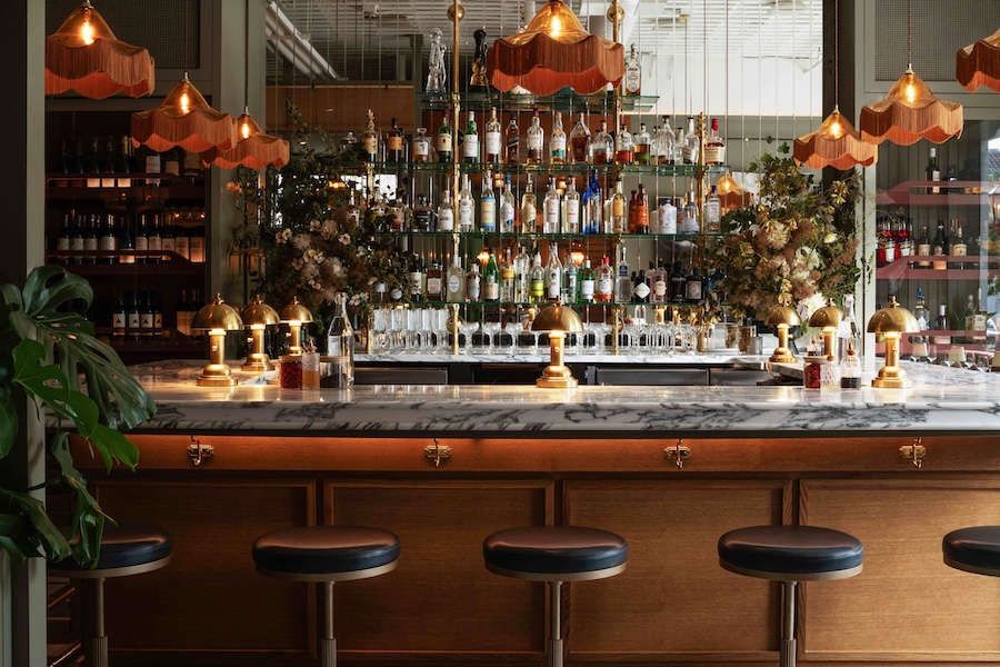 Macarena restaurant silicon valley main dining room statement chandeliers fringe tasseled lampshades marble bar stools flowers plants liquor