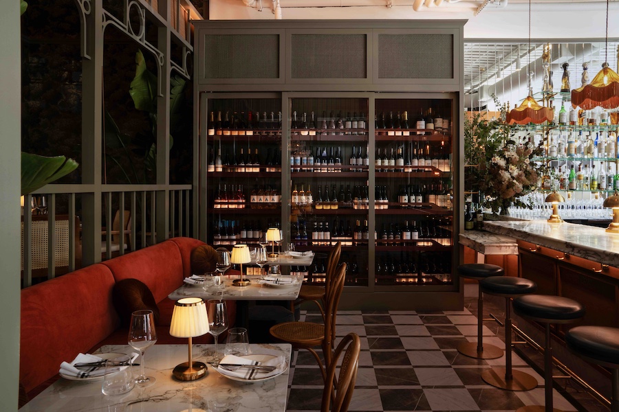 Macarena restaurant silicon valley main dining room statement chandeliers fringe tasseled lampshades marble bar stools flowers plants liquor orange banquette black and white floor